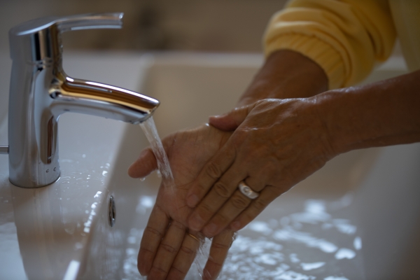 Starsza kobieta myje ręce pod bieżącą wodą